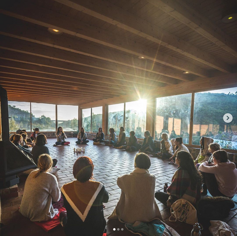 A group of people sitting on the ground in a circle during a retreat at Monte da Orada
