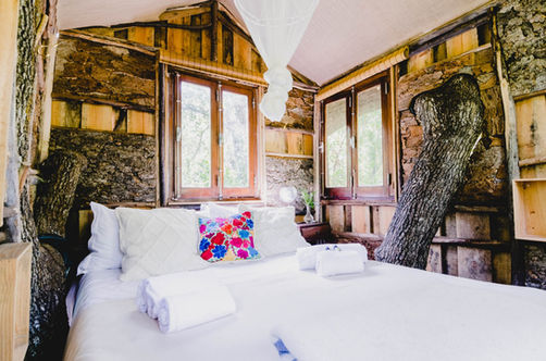Windows and Double bed inside the tree house accommodation at Monte  da Orada Retreat Centre
