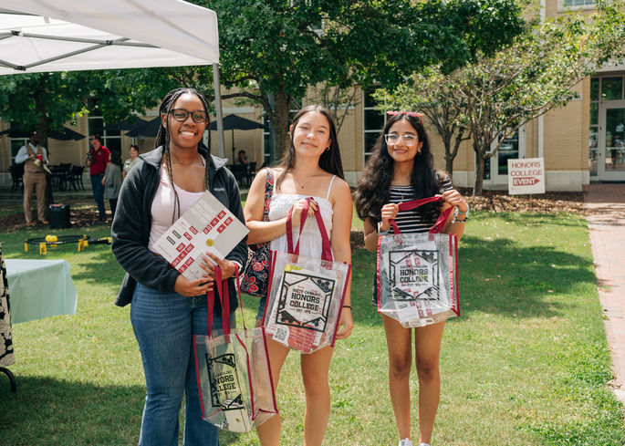 Students holding up clear tote bags.