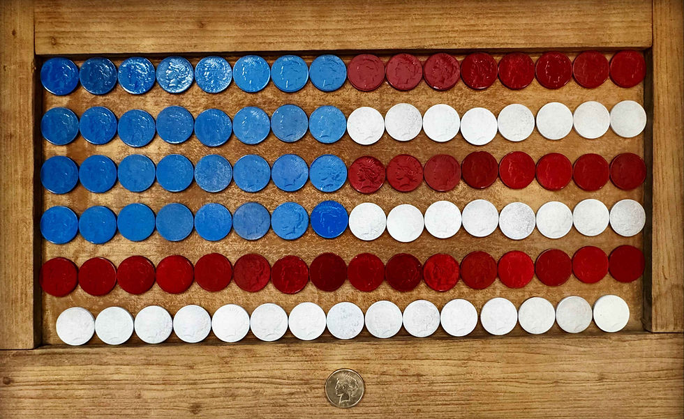 Peace coins painted blue, red, and white are arranged in the pattern of the United States of America flag on a shallow, wooden display.