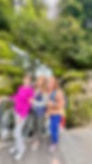 3 female travelers in front of a waterfall on a group trip