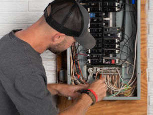 Licensed electrician inspecting and servicing residential electrical breaker panel