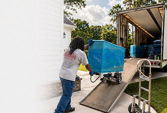 A yarborough's mover pushing a wrapped dresser up the ramp on the moving truck