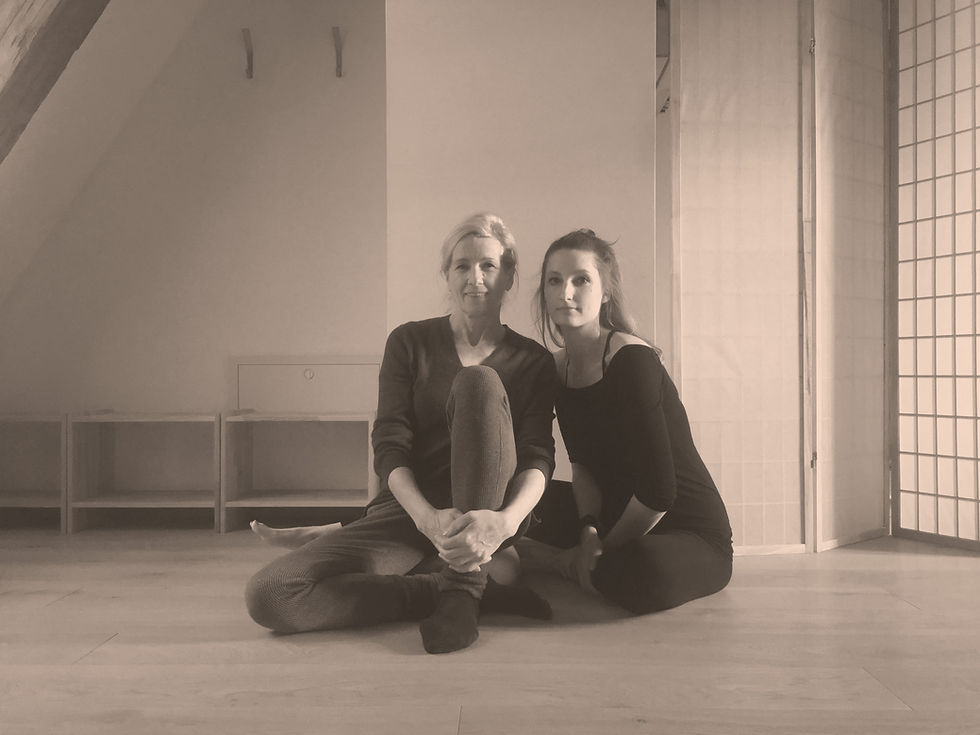 Zwei Frauen sitzen am Boden eines Yogastudios