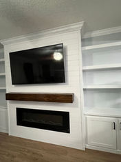 White custom-built entertainment center with TV and fireplace.