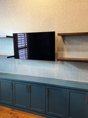 Modern custom-built wall unit with a deep blue-green base cabinet featuring shaker-style doors and two dark wood floating shelves above