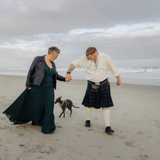 Vow renewal couple meeting a dog on Tomohawk Beach, Dunedin, New Zealand