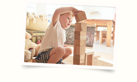 small boy stacking wooden building blocks.