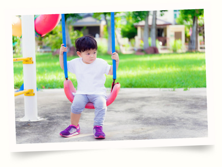 toddler sitting on swing in park
