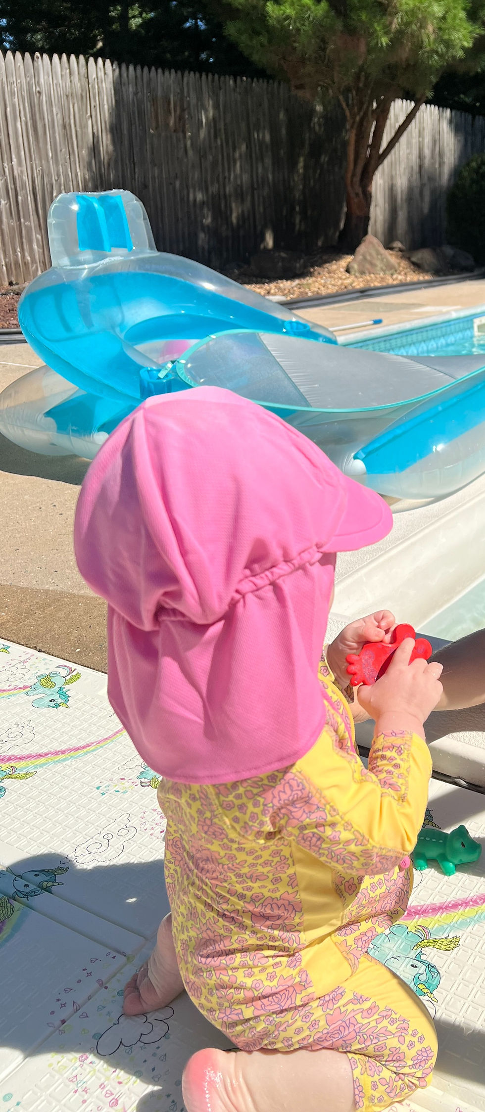toddler in colorful bathingsuit and sun hat