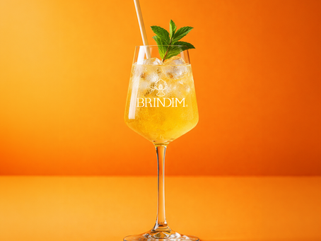 Ein Brindim Mango Spritz Glas vor gelborangenem Hintergrund
