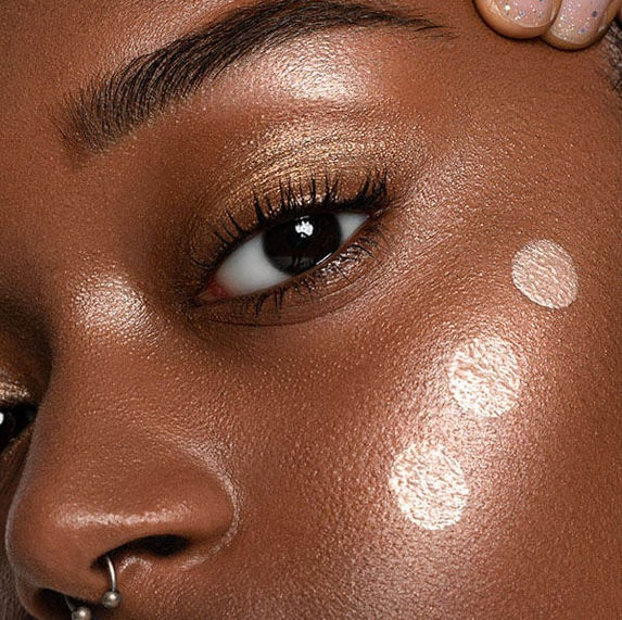 Glowy beauty makeup with highlighter drops on dark skin for makeup brand advertising campaign in London