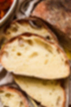 Rustic homemade ciabatta bread with pasta and meatballs in the background