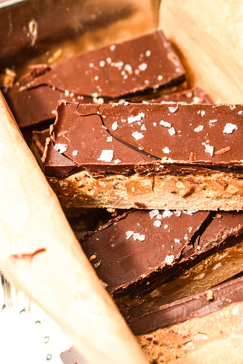 Protein snickers bars with crunchy peanut butter in the background