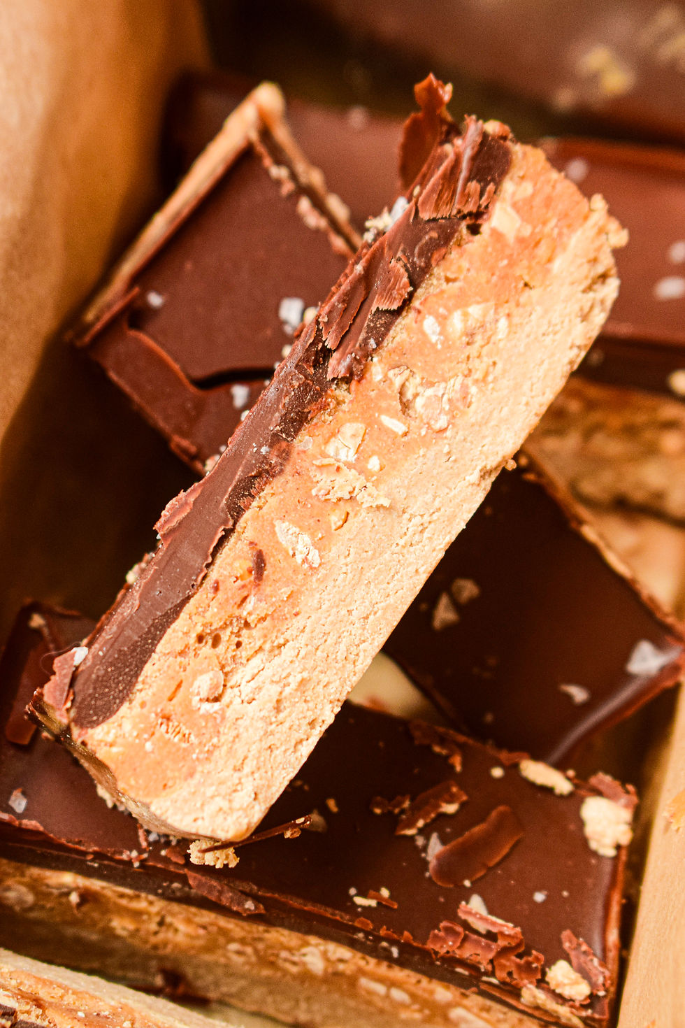 Protein snickers bars with crunchy peanut butter in the background