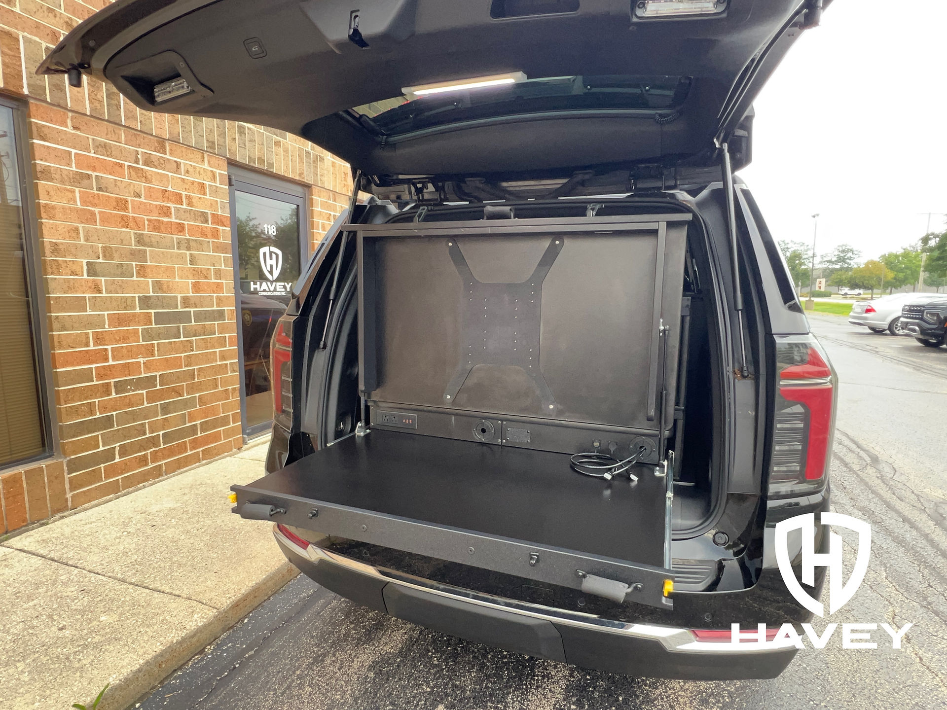 Rear hatch open view of 2025 Chevy Tahoe PPV police drone unit TruckVault drone command cabinet with fold up TV mount and viewing platform.