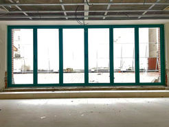 Large green framed windows in empty room showcasing outdoor scenery PROJECTS