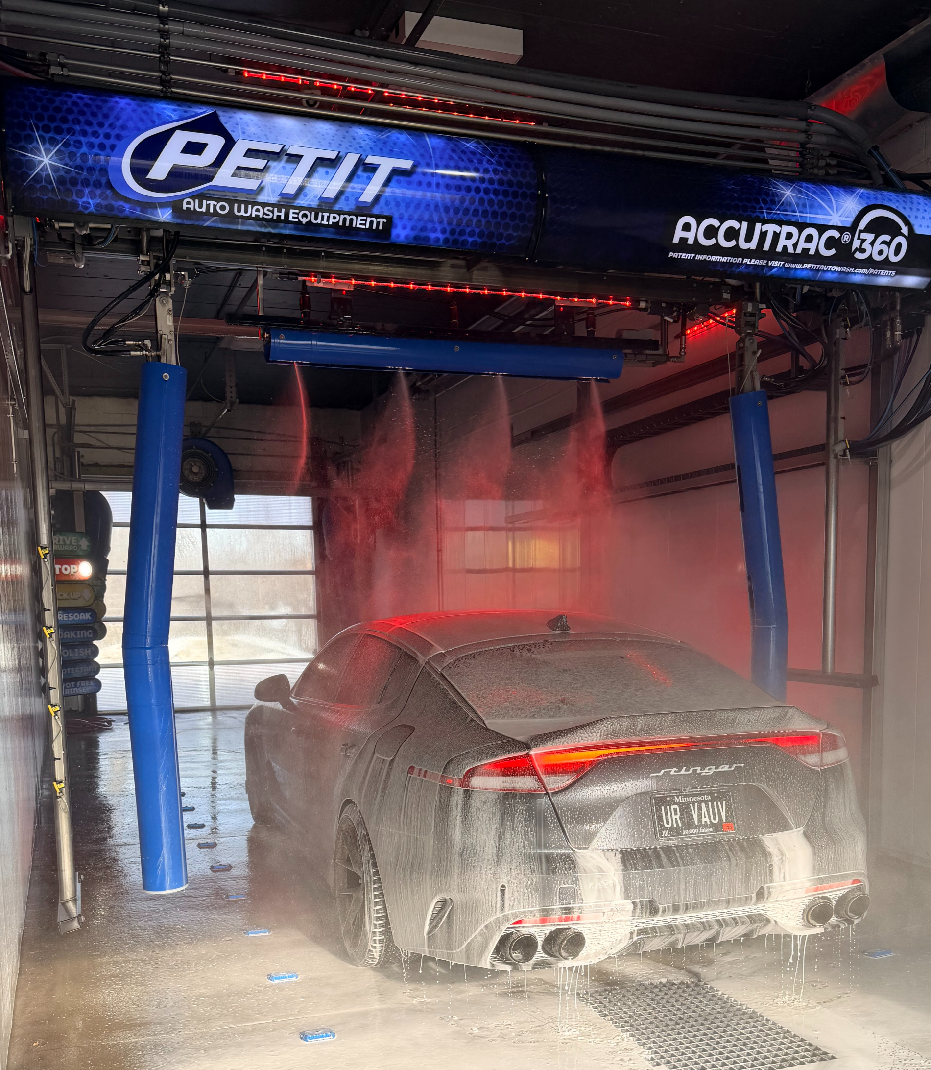 Car being washed under a prominently branded Petit Accutrac 360 system