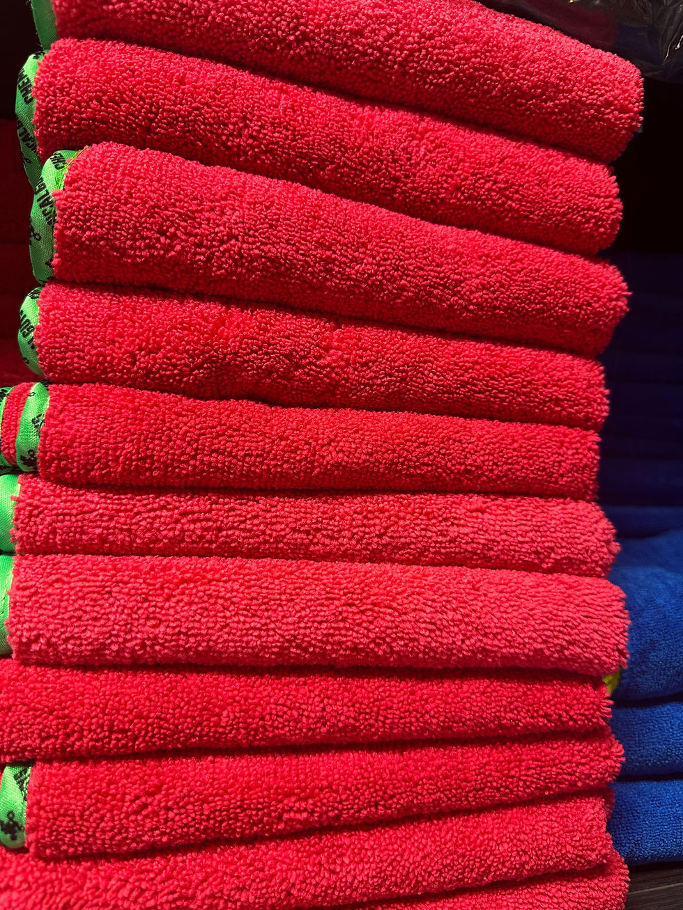 “Assorted car cleaning supplies including spray bottles, microfiber cloths, and brushes on a workbench.”