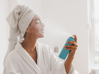朝のシャワー後にミスト化粧水を顔にかけて保湿する女性