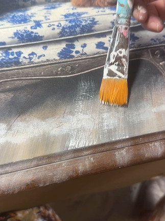 Starting to blend decoupage paper floor edge on brown writing desk for a more finished look