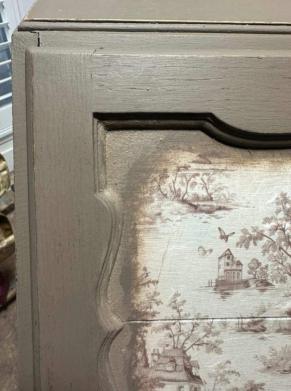 Close up of the blended edge of decoupage paper on brown vintage desk makeover