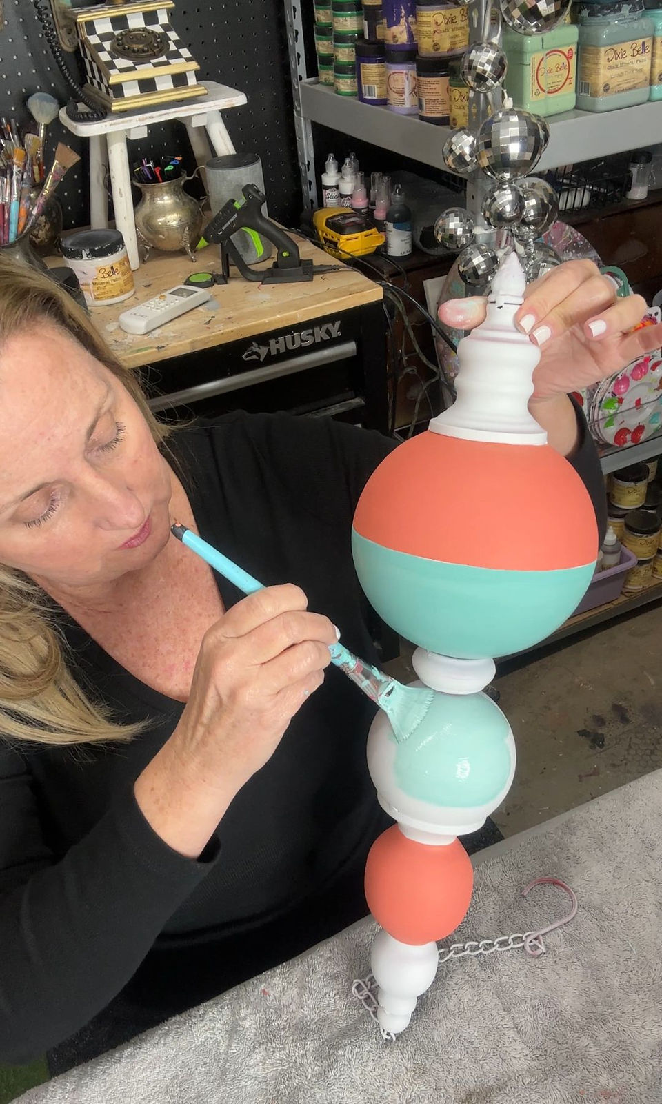 woman painting custom floral design on jumbo finial ornament