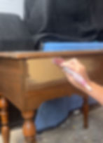 a hand painting a wooden writing desk with brown paint