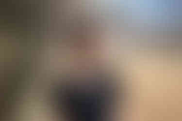 Une femme portant une petite robe noire, avec un haut en dentelle, est dehors, dans un jardin.