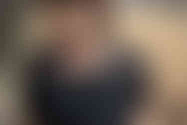 Une femme portant une petite robe noire, avec un haut en dentelle, est dehors, dans un jardin.