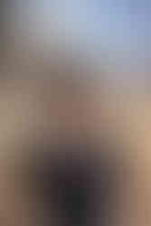 Une femme portant une petite robe noire, avec un haut en dentelle, est dehors, dans un jardin.