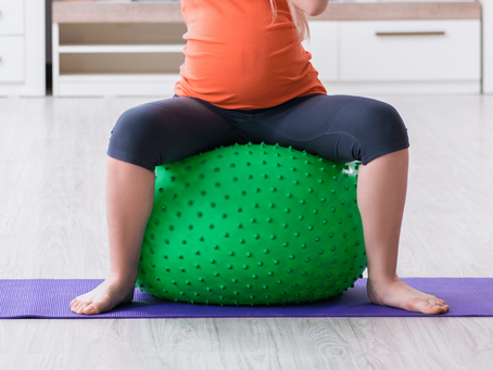 Une femme asssise sur un ballon de fitness