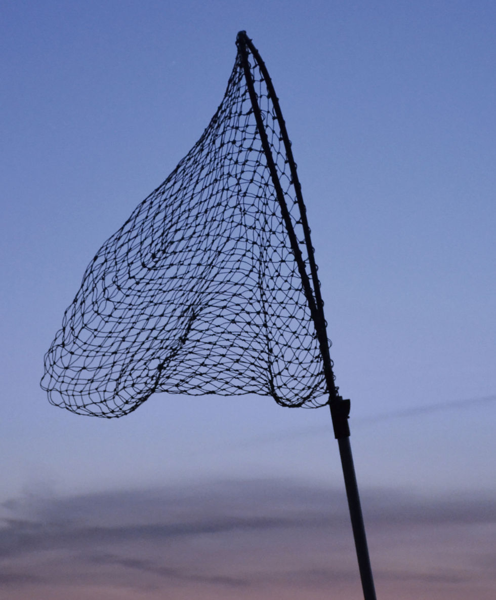 Fishing net silhouetted against a sunset sky with shades of blue, orange, and pink, creating a calm and serene mood.