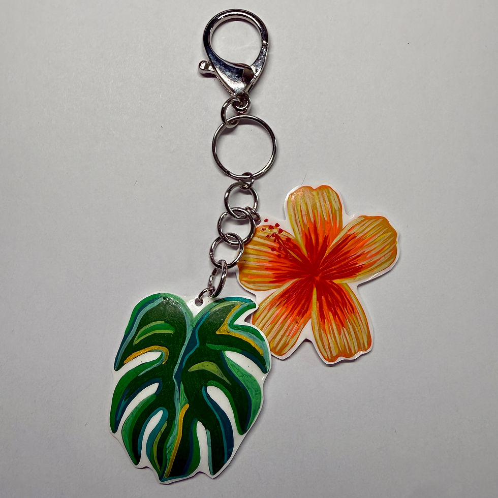 Bag charm with a green monstera leaf and a yellow, orange, and red hibiscus flower