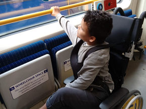 Luis holding a rail in his wheelchair on a tram.