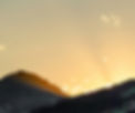 Sunbeams shine over silhouetted mountains at sunset_edited.jpg