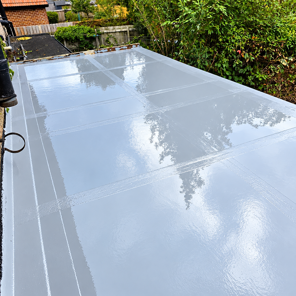 A flat, dark grey roofing surface is installed on a brick house extension with a view of neighbouring homes and trees.