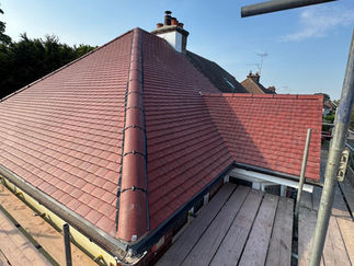 Red plain tiled roof installation on a multi-pitched house