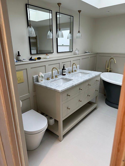 Traditional bathroom installed with cream cupboards and marble tops