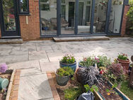 New porcelain patio installation with block paving edging and landscaped planting