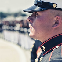 The silhouette of a U.S. Marine in formal wear in front of a line of other soldiers.