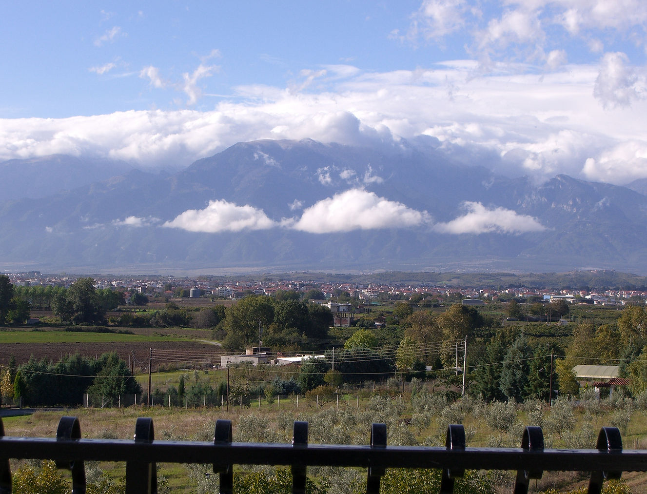 A stunning and mystical view of Mt Olympus washed in ethereal clouds under a blue sky in Fall. the city of Katerini  and distant villages at the base enhance the rare composition..