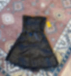 Black sequin dress with a bow on a patterned rug. Yellow price tag reads "Esme". The background has geometric designs in muted colors. Located in North End Halifax.