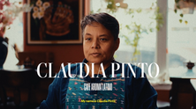A person sits in a café with decorative art and plants. Text reads "CLAUDIA PINTO" and "My name is Claudia Pinto." Calm and inviting setting.