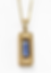 Gold pendant with a rectangular blue gemstone, bordered by textured gold beads, on a gold chain. White background. Elegant and sleek. Located in North End Halifax.
