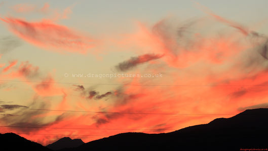 A vivid red sunset behind black mountain edges - real sunset wall decor designed to soothe and inspire.