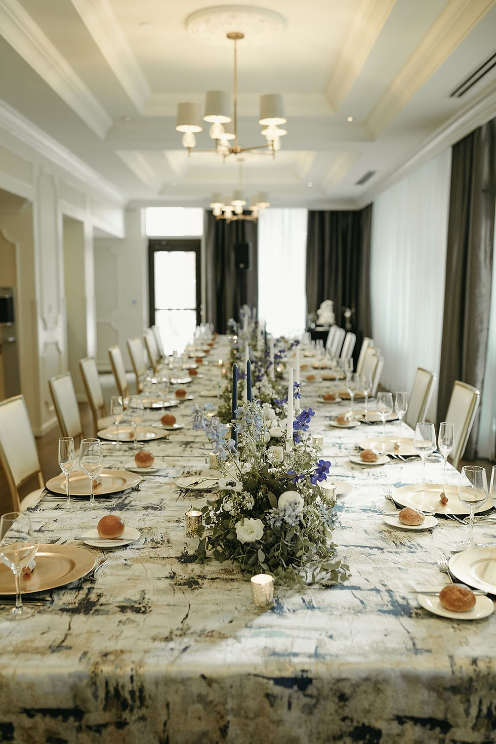 A long dining table, set for thirty guests, is decorated with flowers and candles