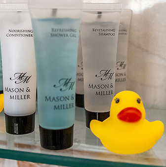 toiletries and two yellow rubber ducks on a glass shelf