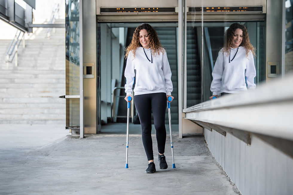 a lady on crutches smiling with stairs behind her