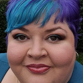 a photograph of a lady with short, blue and purple hair smiling